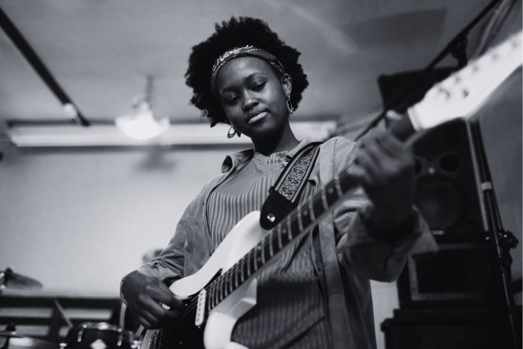 Black woman musician sings and plays acoustic guitar live